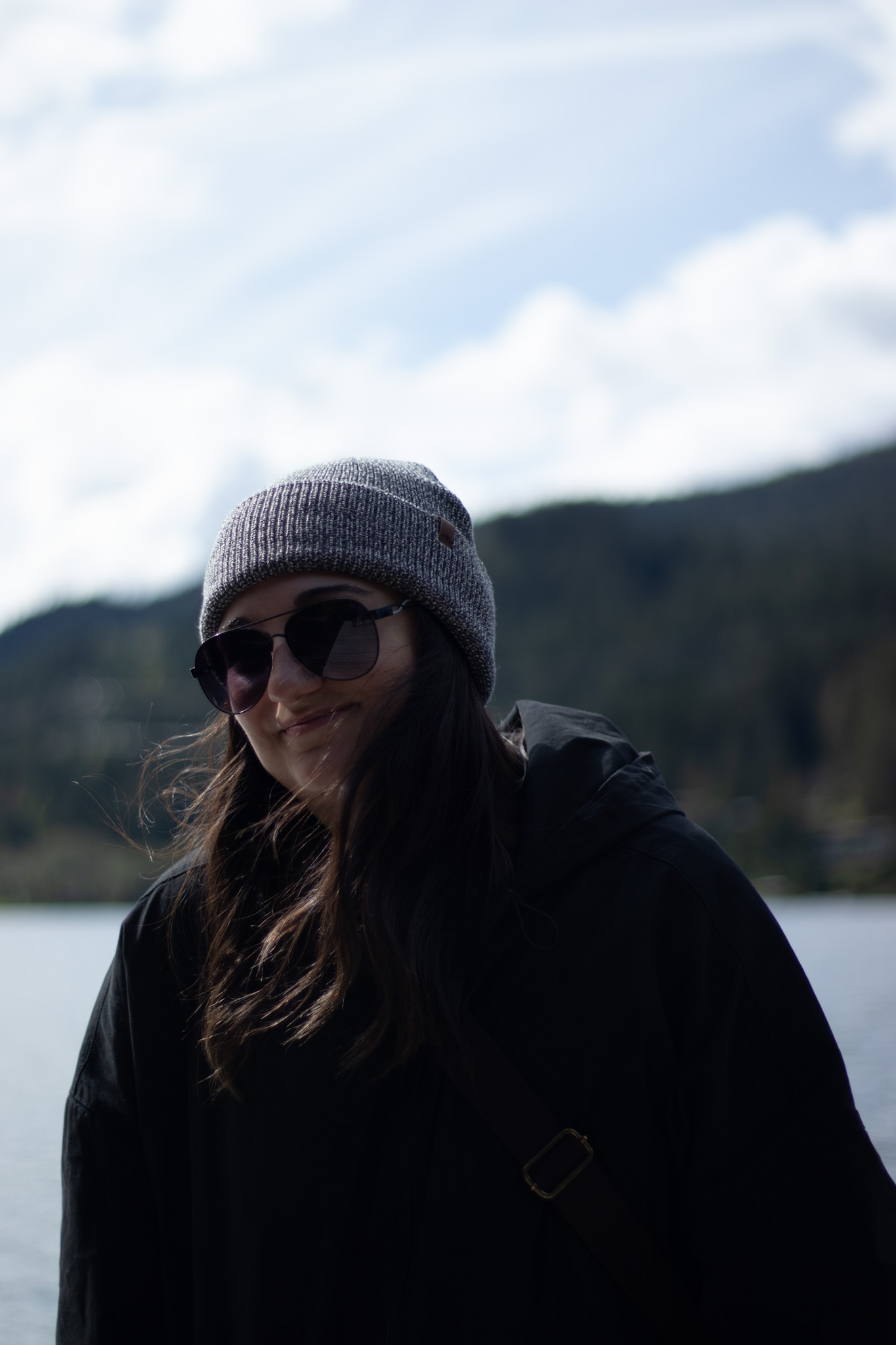 Brunette woman wearing sunglasses, smiling at camera.