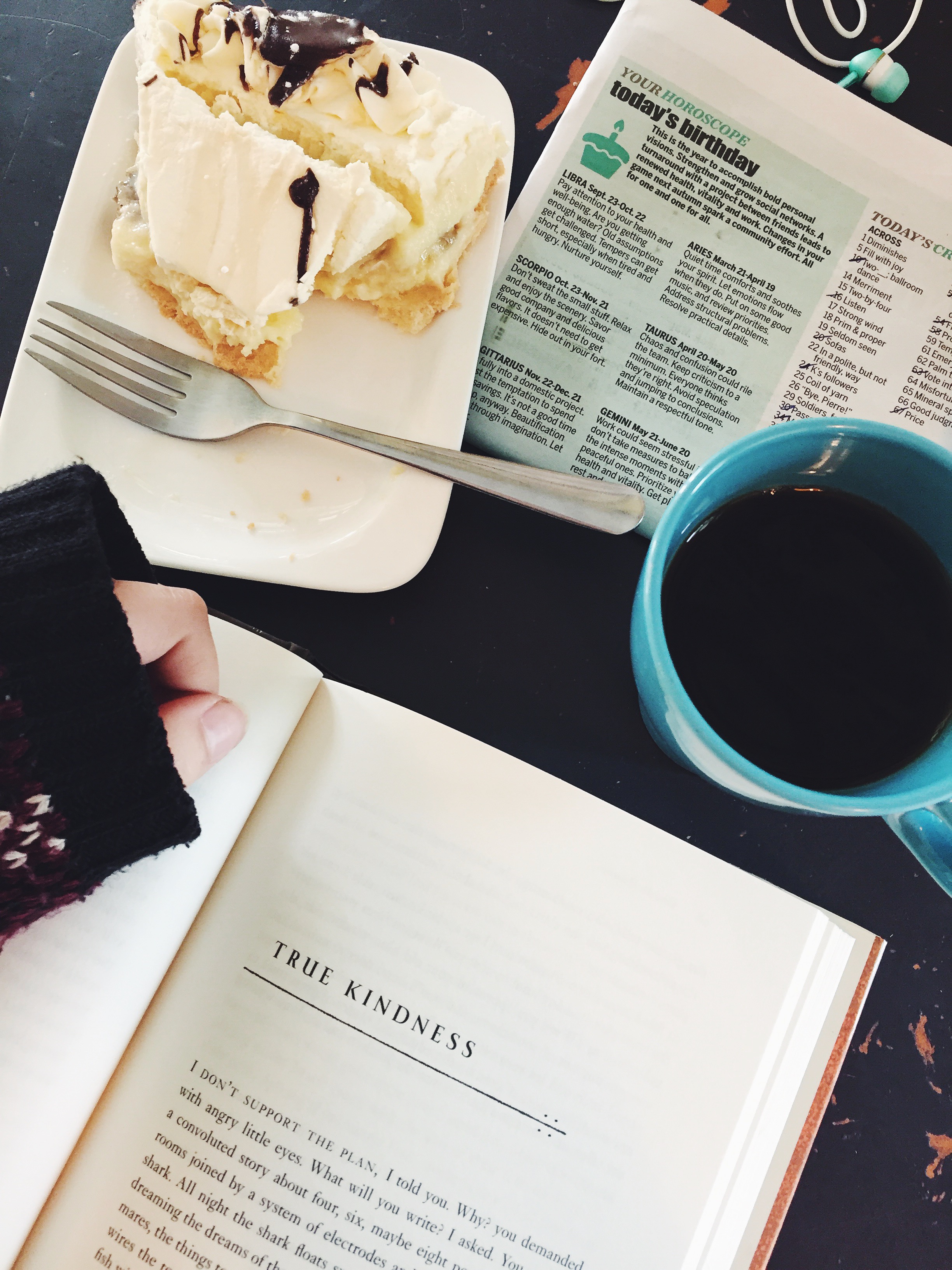 Book, pie, newspaper, and coffee arranged on a table.